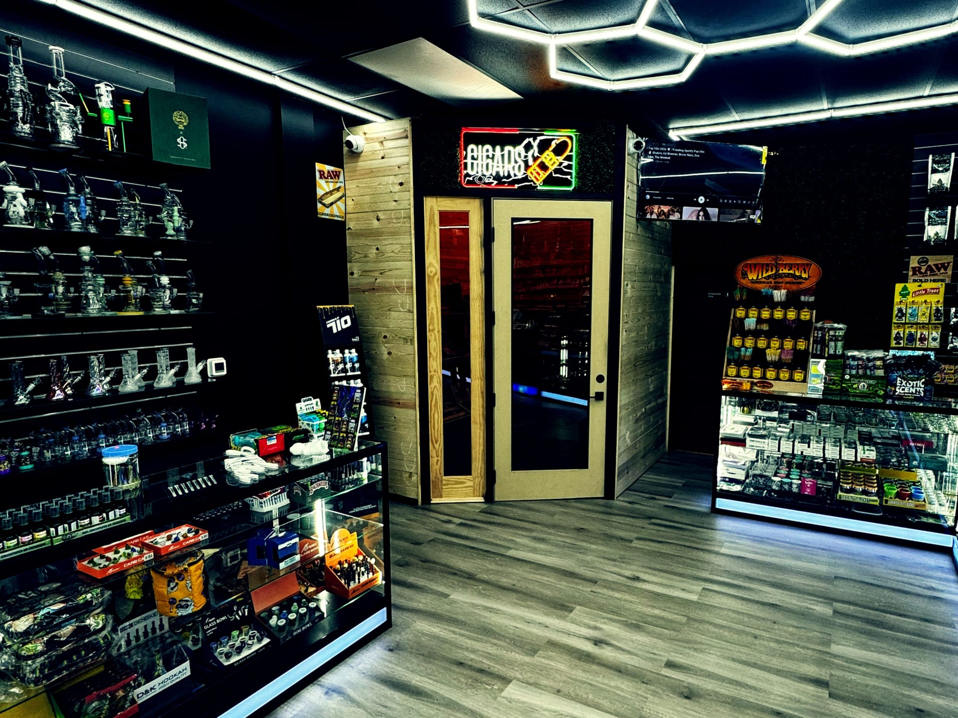 Glass bongs, water pipes, and smoking accessories on lighted shelves at Aura Vape and Cigar.