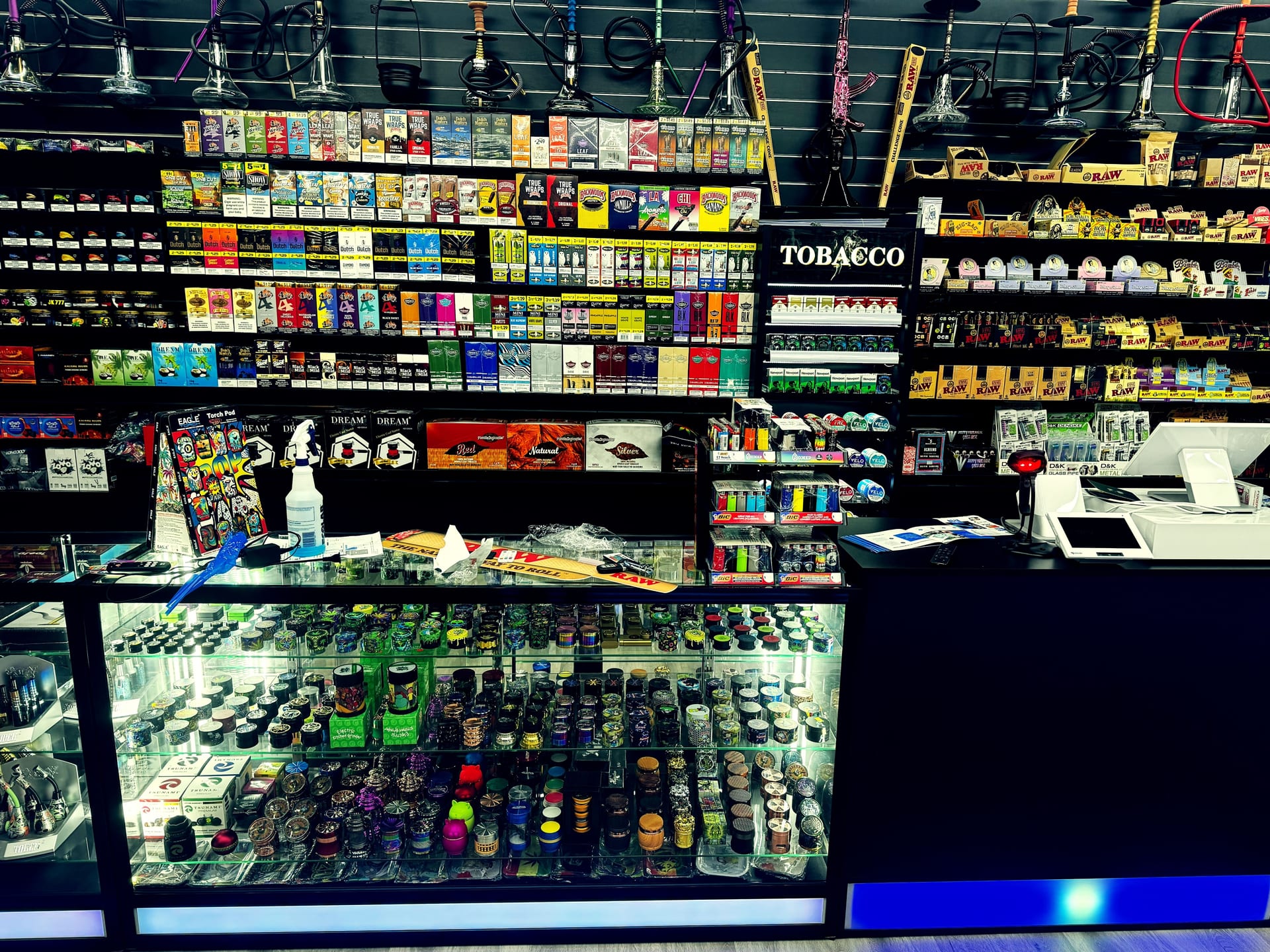 Glass display case filled with multi-color herb grinders and checkout register.