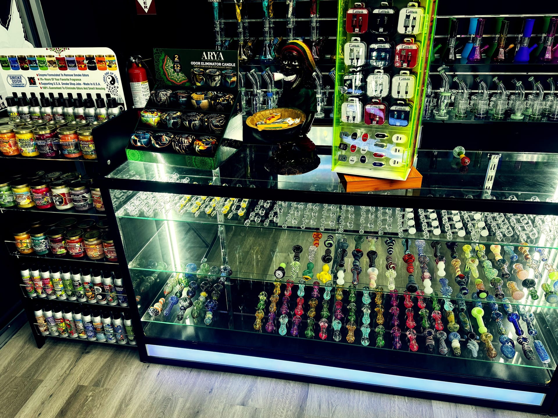 Colored glass hand pipes, Arya odor eliminator candles, and vape chargers.