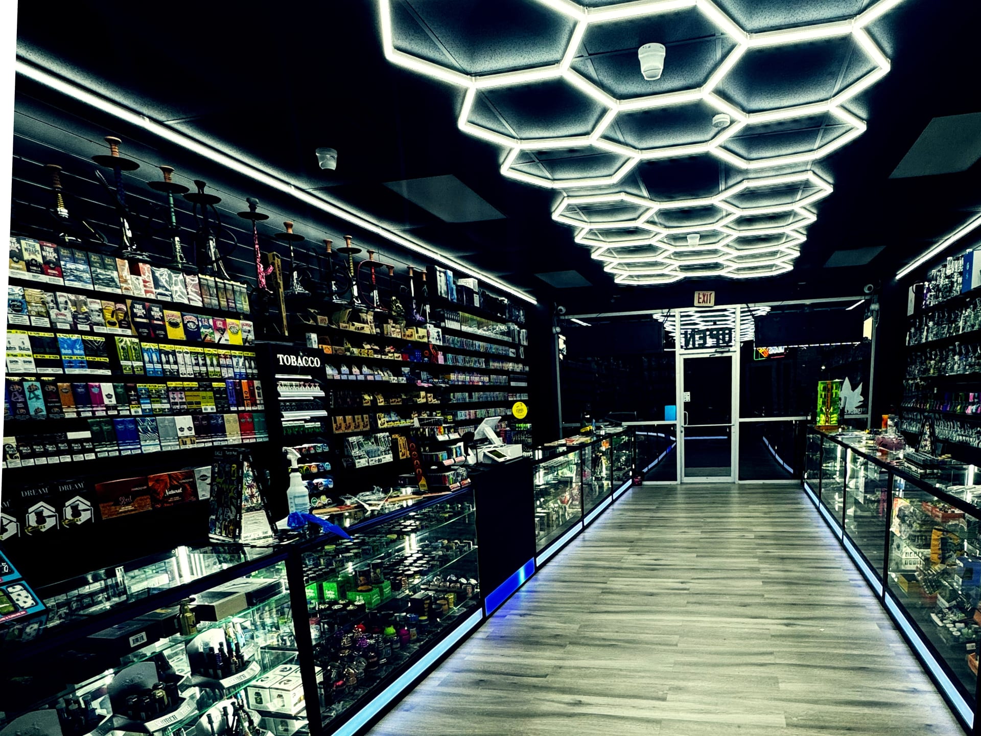 Brightly lit interior aisle with hexagonal ceiling lights at Aura Vape and Cigar, Rock Hill SC.